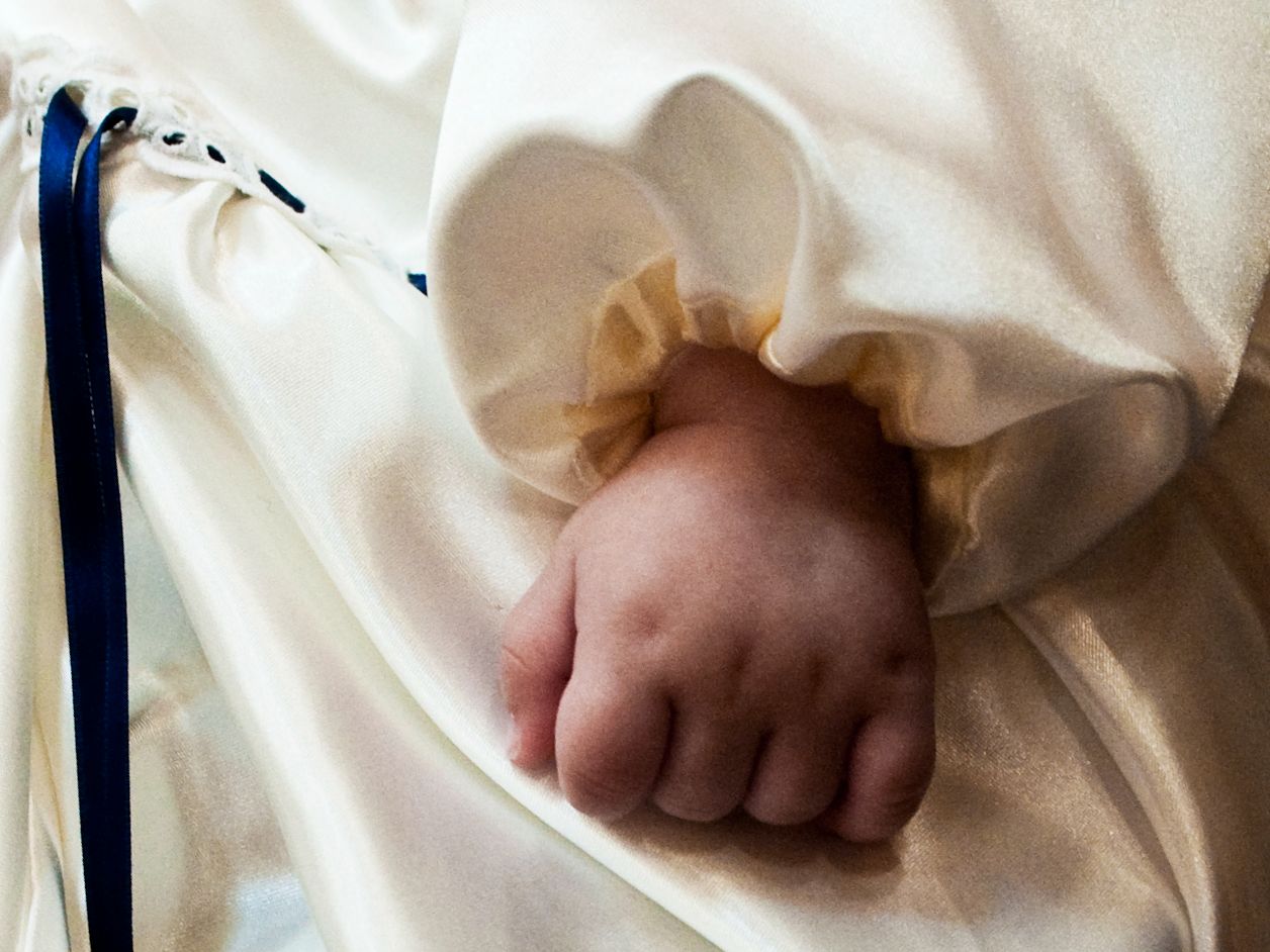 Babyhånd i dåbskjole - folkekirken om dåb